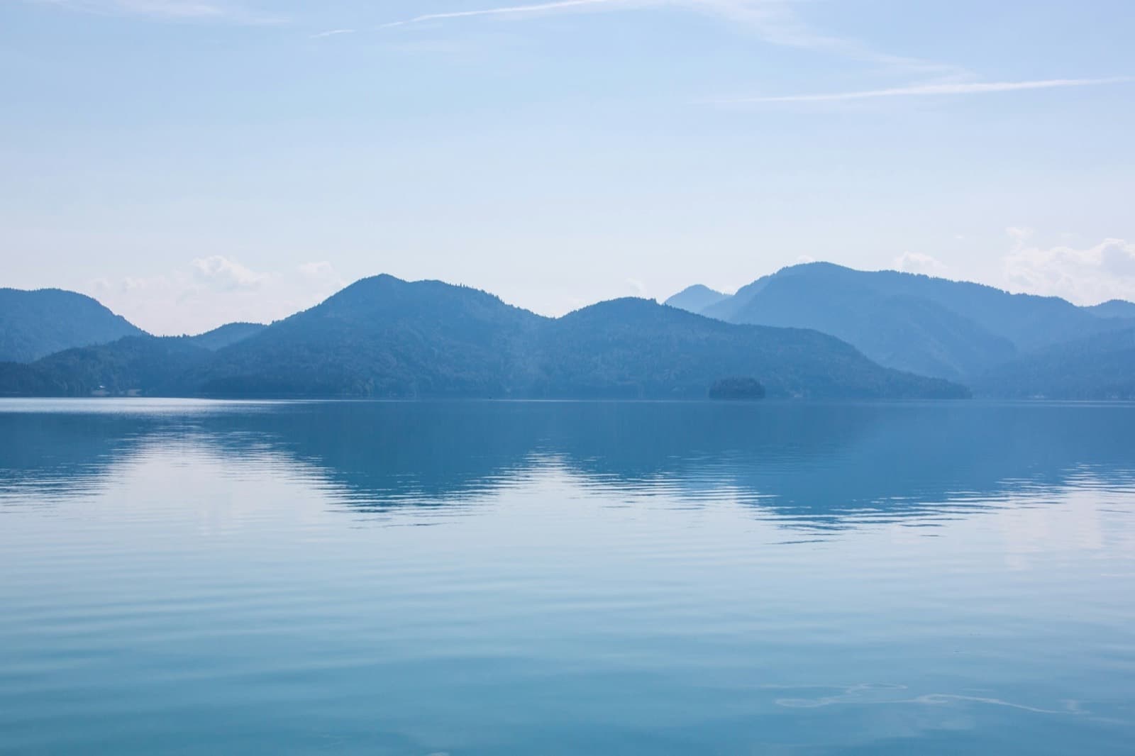 Ruhiger Bergsee mit bewaldeten Höhenzügen – ein Ziel für Tagesfahrten